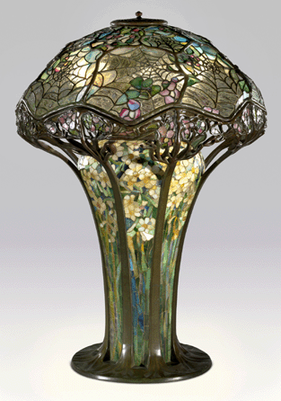 A cobweb encloses a bunch of bright daffodils in the leaded glass, bronze and mosaic glass table lamp designed by Clara Driscoll.