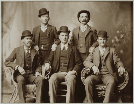 Standouts among outlaws of the West, "The Wild Bunch†gained lasting fame for their daring robberies and escapes from law enforcement. Among those pictured here in dapper suits likely purchased with proceeds from a bank heist are, seated far left, Harry Longabaugh ("Sundance Kid  and seated far right Robert LeRoy Parker ("Butch Cassidy). Photo, 1900, by John Swartz. National Portrait Gallery.