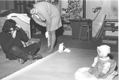 In 1974, Jane was involved with a research project at Old Sturbridge Village on infant clothes. Using a pattern book, The Workwoman's Guide published 1838, she and staff there made a full set of infant's clothing and documented the use of each piece. Here, she looks on as OSV photographer Donald Eaton photographs a very young Tim Nylander, who helped out his mom by modeling the outfits.