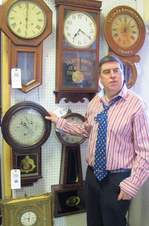 Tim Chapulis, owner and auctioneer, points out lot 255, a Gale astronomical clock with four dials from the Welch Clock Company, Forestville, Conn., which struck a high note at $6,900. 