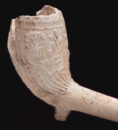 Fluted pipe with vertical milling around the rim and a wheat sheaf between floral decorations on the side of the bowl, circa 1810‱840, made in Chester. Attesting to both their popularity and fragility, 1,470 fragments of clay tobacco pipes were found on the project site. Though pipes are utilitarian objects, their design, decoration and maker's marks can be seen as icons for the brief period of time in which each was manufactured and used. New York Transit Museum.