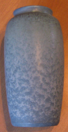 Hampshire Pottery vase signed by Emma Robertson, circa 1904‱0, Keene, N.H. It is approximately 8½ to 9 inches tall with a bulbous body and features a blue glaze matte design that has a mottled texture. On the bottom of the vase are the artist's markings: a big "M†and small "A.• style=