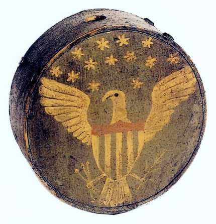 The wooden canteen from the War of 1812, similar to the one shown here, is a painted militia cheese box canteen featuring 13 stars above a displayed eagle on a blue ground. 