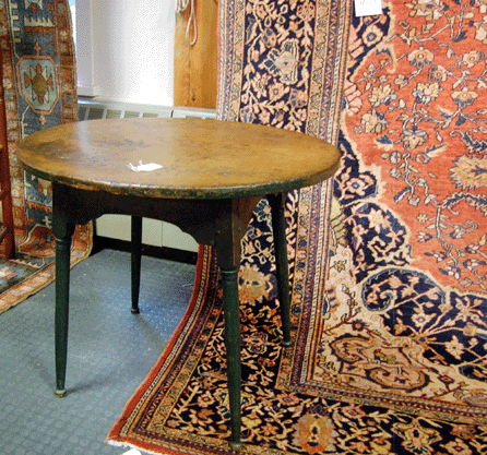 An Eighteenth Century New England pine and birch tavern table realized $805. It is pictured among the rugs and carpets that brought some very good prices, the highest of which was the Persian serape that sold for $12,075.