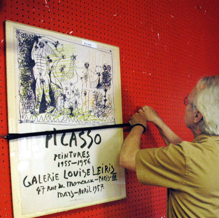Gallery staff member Tom Curran hangs a Picasso poster for preview. The poster sold for $200.