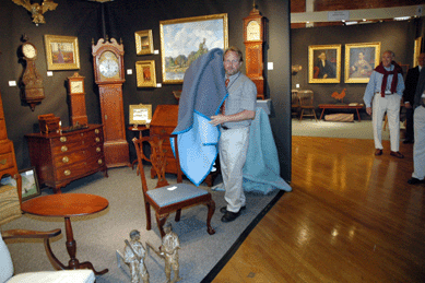 "We don't uncover our special things until the very last moment,†Scott Bassett said, "as people can see into our booth from the entrance door.†A chair and a tilt top table were the Thursday morning additions to the booth of Peter Sawyer Antiques.