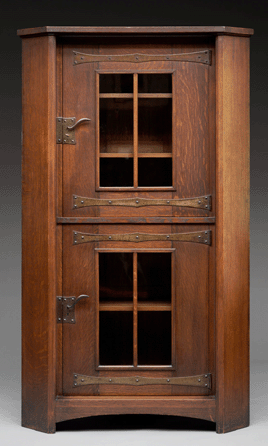 Replacing the Victorian predilection for decorating with a miscellany of fancy objects, Gustav Stickley opted for designs in plain, straight lines that were adaptable for Craftsman settings. This oak, iron and glass corner cupboard was executed around 1902‱903 in Stickley's favorite brown color, achieved by applying wax or a thin coat of shellac to give the wood a soft, lustrous glow. Private collection. ⁁ll photos courtesy of Dallas Museum of Art.