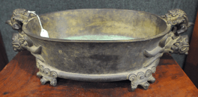 A Seventeenth Century oval dragon footed Chinese bronze brazier with dragon-form handles brought $36,800.