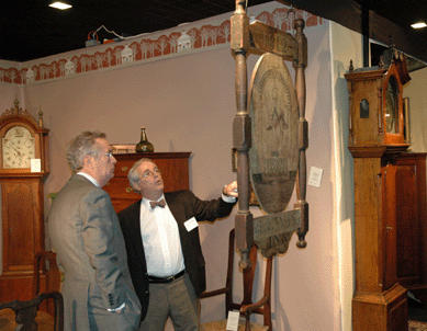 Always the salesman, Arthur describes the fine points of an early trade sign and highboy at recent shows.
