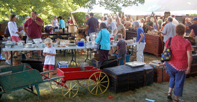 The sale attracted a very large crowd, drawn by the disparate objects. A young man eyes the child's buckboard wagon that sold for $403. The blue painted wheelbarrow was $92.
