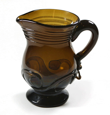 The large olive-amber pitcher with a lily pad decoration was made at Stoddard in the 1850s by Matt Johnson.