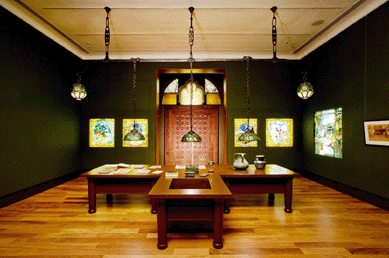 A view of the living room gallery in the Morse installation, as seen from the Reception Hall gallery, showing the turtleback globes and hanging shades, lunette window and Four Seasons window panels.