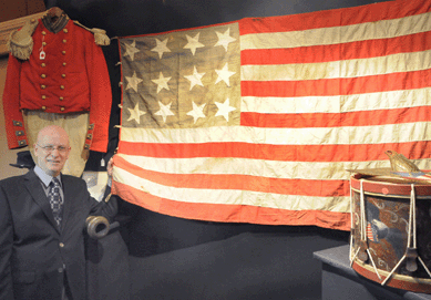 Auctioneer Louis Dianni with a Confederate Secession 12-star flag that sold for $8,050. The Civil War-era drum, right, brought $2,070, while a grouping of Civil War material belonging to Francis Lord, Salem, Mass., including his cadet's uniform, realized $10,925.