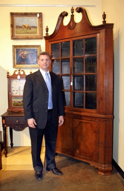 A bull market in Southern decorative arts has created broad interest in the arts of North Carolina, a specialty of auctioneer Leland Little. This intriguing North Carolina walnut corner cupboard, a new discovery, dates to about 1820 and shows characteristics of both Davidson and Guilford County furniture. Its inlaid pediment relates to a documented John Swisegood corner cupboard at the Museum of Early Southern Decorative Arts in nearby Winston-Salem. Its applied waist, lower panel door and feet are closer to work by John Adams of Guilford County.  Original and intact, it brought $16,100. To Little's left is a Bedford County, Va., cherry stand, $1,610. Above the stand is "Allegory†by Elliott Daingerfield, a North Carolina artist, $12,650. "Yellow Cow,†$1,725, is by Connecticut artist John Carlton Wiggins.