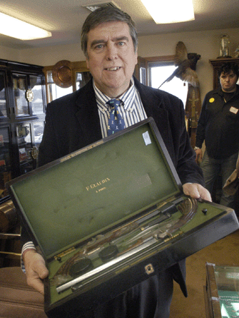 Auctioneer Tim Chapulis shows off a pair of dueling pistols that tied with the Hiram Welton clock as top lot, selling for $7,670.