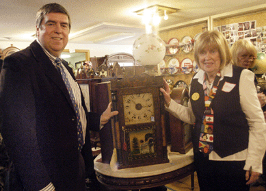 Tim and Helen Chapulis pose with the Hiram Welton shelf clock that tied for top lot of the sale at $7,670.