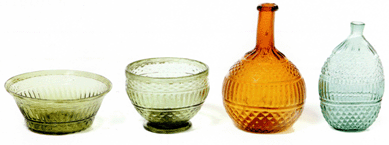 Interestingly, all of these pieces of glassware were blown into the same three-part mold at the glass works at Kent, then formed into different objects. From left, the bowl with folded rim is in light green, the punch bowl is in a natural yellow-green, the glob is in amber and the flattened flask is aqua. Collection of the Ohio Historical Society.