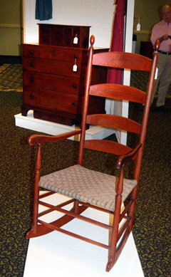 The birch rocking chair with the original red painted finish, elongated candle flame finials, four graduated slats and bold rockers from the collection of Walter S. Bucklin brought $43,875.