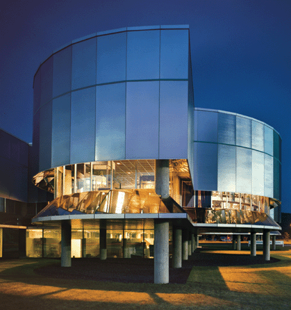 An evening view of the Corning Museum of Glass with the Gunnar Bikerts-designed addition that was conceived in 1979 and created a flowing series of galleries with the library at its core.