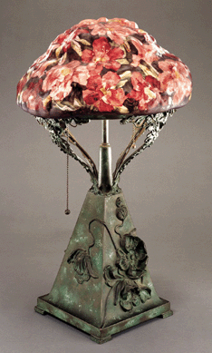 After 1902, the Pairpoint Corporation greatly increased its production of lamps, most of which were electric The elaborate metal bases were made at the original Pairpoint factory and the reverse painted shades were made and decorated in the glasshouse. The floral "puffy†shades were mold-blown to imitate the shapes of flowers or fruit and then enameled on the interior surface. Gift of the New Bedford Glass Society Inc.