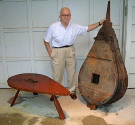 Val Jacobsen stands with an old bellows and a coffee table he crafted from another bellows. Besides trading in antiques, he expressed his artistic side, crafting bellows tables.