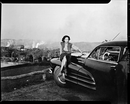 Charles "Teenie†Harris (1908‱998), "Woman seated on car, with steel mill in background,†circa 1940‱946. Teenie Harris Archive ©Carnegie Museum of Art.