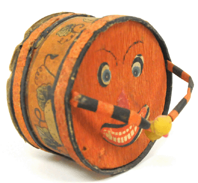 A remarkable candy container in the form of a drum with jack-o'-lantern crepe paper face and moveable drumstick arms.