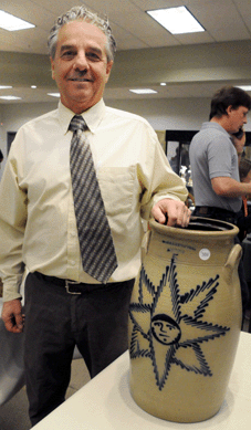 Auctioneer Sam Cottone shows off the rare Harrington, Lyons, N.Y., 5-gallon stoneware churn with star-face decoration, picked fresh out of a local home, that sold for $14,950.