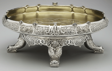 This fancy ice cream dish, encrusted with flower ornaments and standing on four elephant trunk feet, was one of a pair made around 1877‱878 by Tiffany & Co. from silver ore excavated from a Nevada lode owned by mining baron John W. Mackay. It was part of the Mackays' 1,250-piece dinner set, "the most extravagant silver service of the Gilded Age,†says Hofer. It was reported that 200 Tiffany craftsmen worked exclusively for two years on the set, a grand symbol of Gilded Age excess.