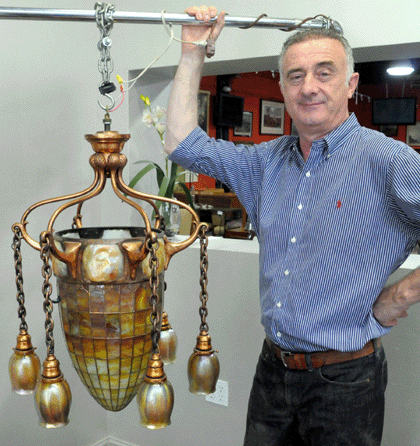Auctioneer Ronan Clarke with the top lot of the auction, the leaded glass chandelier by Tiffany Studios that was consigned from a home in Garrison, N.Y., where it had hung for the past 30 years. The rare lighting fixture sold in the room at $102,000.