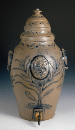 An early Nineteenth Century stoneware cooler with applied patriotic eagle centered in an elaborately incised and cobalt-filled tree attributed to a Perth Amboy, N.J., maker. The dome lidded cooler is inscribed "T. Whiteman†and "1853†(three times). Plant and bird motifs are traditionally associated with goodwill and plenty. The fish on the back may symbolize drunkenness. Bequest of Henry Francis du Pont. Courtesy Winterthur.