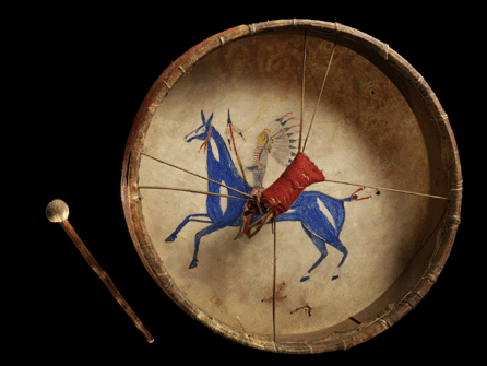 This brightly colored drum was made in North or South Dakota around 1860. Many times used to communicate with the Creator, these instruments contained drawings that memorialized a favorite horse. Using pigment, rawhide, wood, wool cloth and sinew, this instrument vividly depicts an Indian brave in full war regalia atop his comrade in battle.