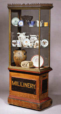 Lot 592 was a paint decorated "Millinery†cabinet, American, late Nineteenth Century, the top section constructed of cast iron, brass and tin, on a paneled wood base with old surface, 70½ inches high, 27 inches wide and 16 inches deep. The provenance lists Victor Weinblatt and the piece sold for $3,900, above the $1,500 high estimate.