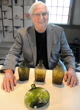 Auctioneer Norman Heckler with some of the top lots. The Jared Spencer flasks realized $111,150, $78,390, and $109,980, and the concentric ring eagle flask, front, brought $19,890.