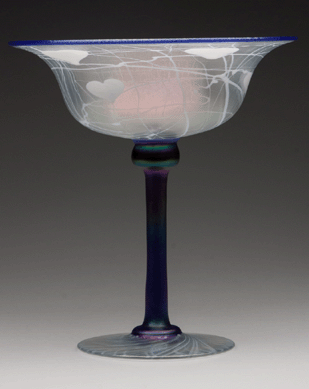 The decorated freehand compote sold for $3,738 against an estimate of $500/800. The iridescent colorless example featured opal hanging hearts, cobalt blue rim and tall stem, unlisted shape and polished pontil mark. Imperial Glass Co., circa 1925, 9 7/8 inches high.