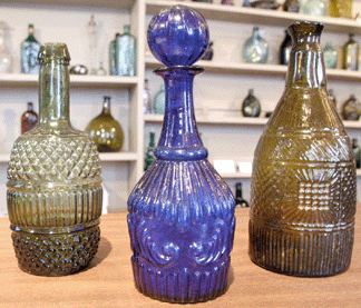 A Sandwich blown three-mold decanter in an attractive cobalt blue, center, GV-8 pattern, retained the original blown stopper and sold for $4,600. The blown three-mold bottle, left, sold for $1,265, and the Keene decanter in olive, GIII-19, brought $2,300.