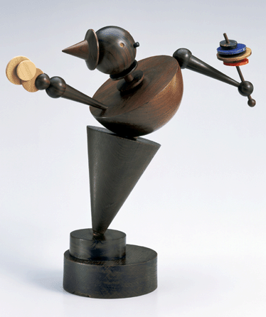 During his six years at the Bauhaus, German artist Eberhard Schrammen created this charmingly playful "Maskottchen (Mascot),†circa 1924, made of turned oak and miscellaneous exotic woods with colored and gold lacquer animating the objects in the figure's hand. Standing a pert 14 9/16 inches tall, "Mascot†recalls the high spirits and sense of humor that often prevailed at the financially strapped school. Bauhaus-Archiv Berlin. ⁇unter Lepkowski photo, ©Estate Eberhard Schrammen