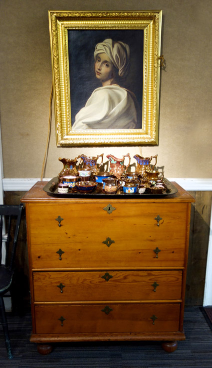 A portrait hung over this four-drawer chest, which was covered by a large selection of copper luster that sold for $ 143.
