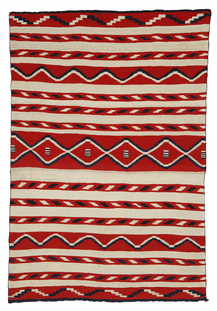 Small format blanket (child’s), Diné (Navajo), 1870s; weft-faced plain weave or tapestry weave, handspun wool warp, handspun natural white, indigo-dyed blue and raveled red wool weft. Alfred M. (A.M.) Camp Collection, Center of Southwest Studies, Fort Lewis College, Durango, Colo.