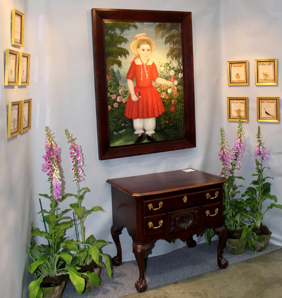 “Girl in A Red Dress,” an unsigned portrait of circa 1850, hangs over a lowboy at Kelly Kinzle Antiques. The New Oxford, Penn., dealer sold the group of nine illustrated leaves from an 1810 book recording the births of members of the Caldwell family of Elkrun, Ohio. James Caldwell and his wife, Rebecca, migrated from Pennsylvania to Ohio in 1809.