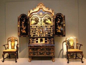 An English George I japanned cabinet of circa 1720, flanked by a pair of blue-japanned armchairs attributed to Giles Grendey, circa 1750. Apter-Fredericks, Ltd, London