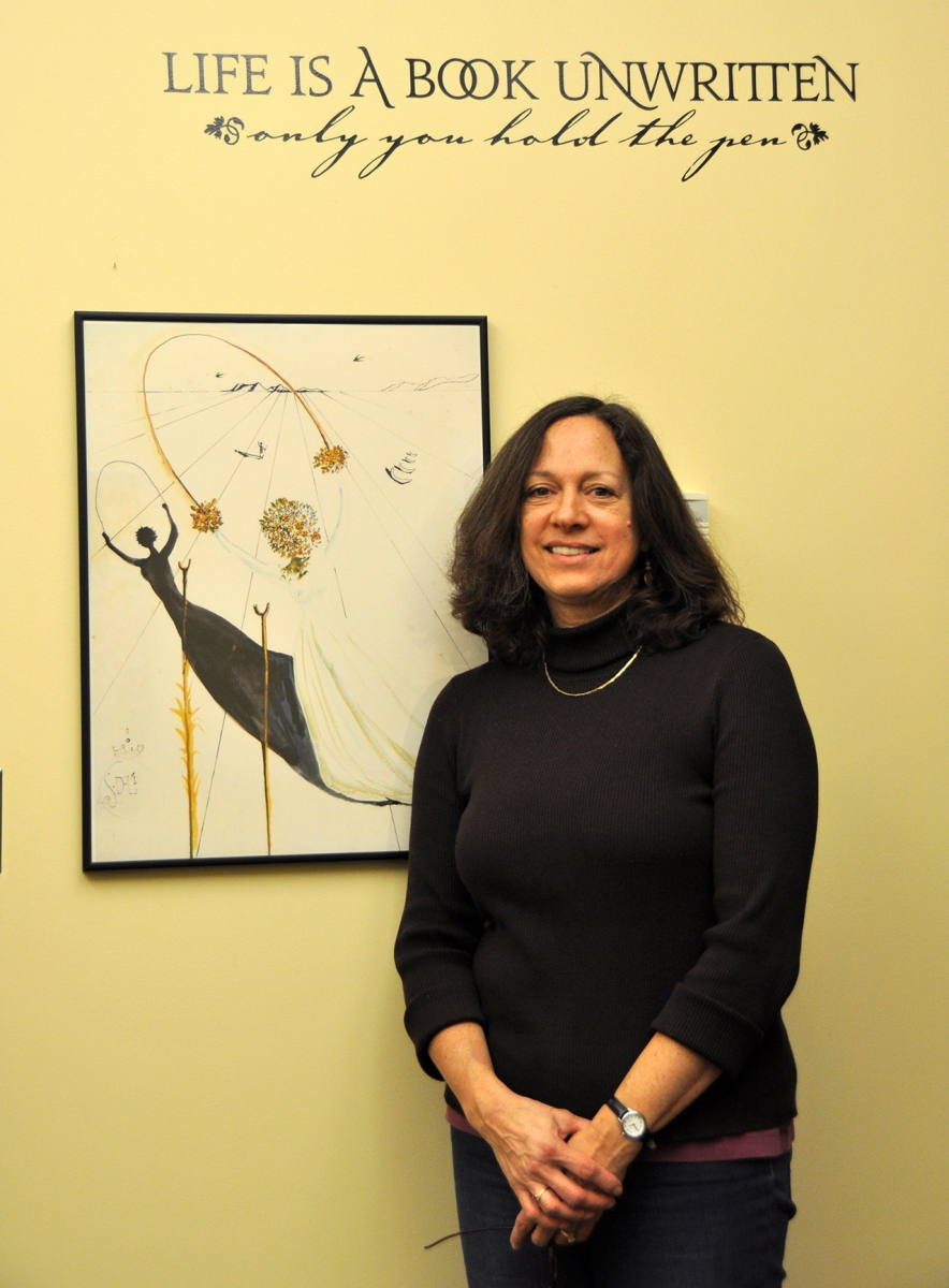 Dr Ellen Schaefer-Salins stands with Alice-related artwork in her office at Salisbury University in the form of a print by Salvador Dali.