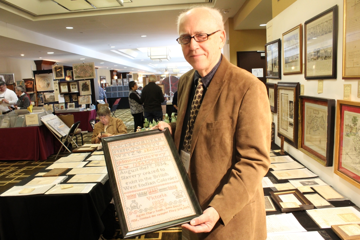 Bill Subjack of Neverbird Antiques holds up one of the many sampler highlights, this one wrought by Agnes Mary Smith in 1837 referencing the end of slavery in the British West Indian colonies in 1834.