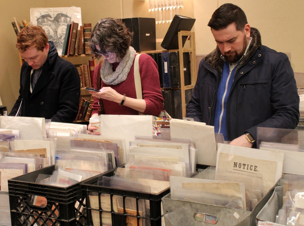 The usual posture at ephemera shows is head-down, and that is the case with these shoppers browsing the burgeoning booth of Peter Luke, Baltimore, N.Y., although the person in the middle may be doing some electronic multitasking.