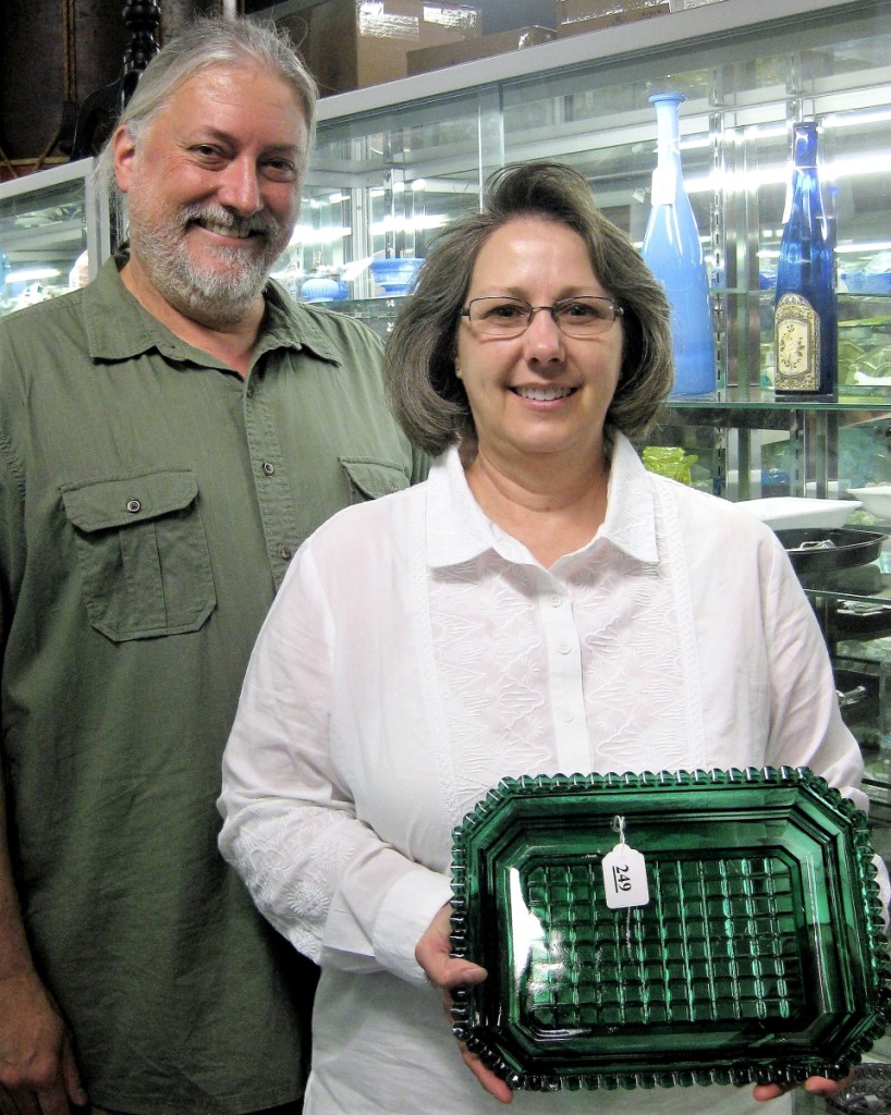 Standing with husband, Jeff, Beverley Evans shows off a favorite Kaiser lot. The large emerald green pressed inverted waffle dish, probably Sandwich, 1840–50, brought $2,808.