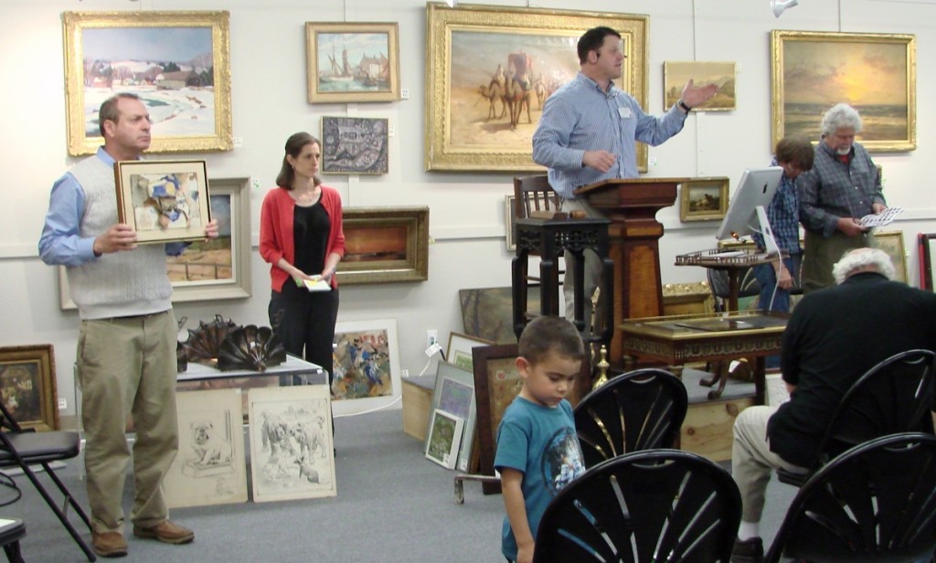 Brett Downer holds the mixed media collage by John Angus Chamberlain, which was the highest priced item in the sale. Doug Stinson is at the podium.