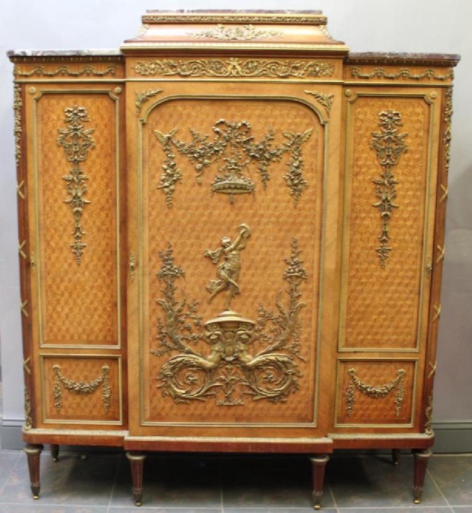 A signed example by Francois Linke, this three-door cabinet performed very well in the current market at $22,500. It featured ormolu mounts to all faces and edges, as well as parquetry inlay door fronts.