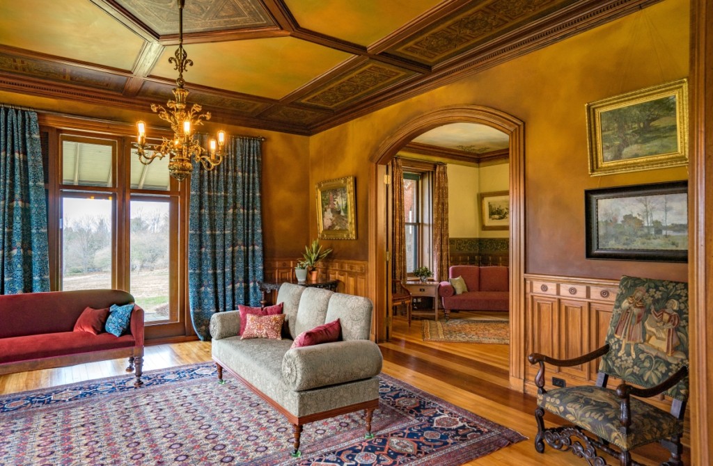 In the large parlor, the circa 1880 Dutch or German brass chandelier was likely installed when the house was built. It has been fitted with period-appropriate replicas of Edison-type bulbs. The sofa, a Eustis family possession, is upholstered in a reproduction William Morris “Crown Imperial” wool and dates to 1880–1900. The Tudor or Jacobean Revival armchair was probably made in Boston between 1870 and 1900. The 1920s Hamadan carpet is of wool, camel hair and cotton. The textile used in the portieres is a reproduction of Morris’s “Bird.”All objects identified in the photographs are in the collection of Historic New England. Photos courtesy Historic New England.