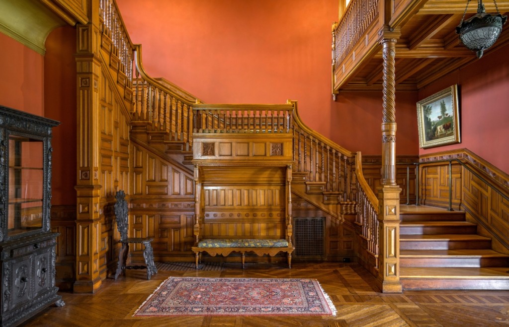 In the massive three-story hall, the carved woodwork and built-in benches are of oak. Paint analysis revealed the original red on the walls and green in the cove below the cornice.