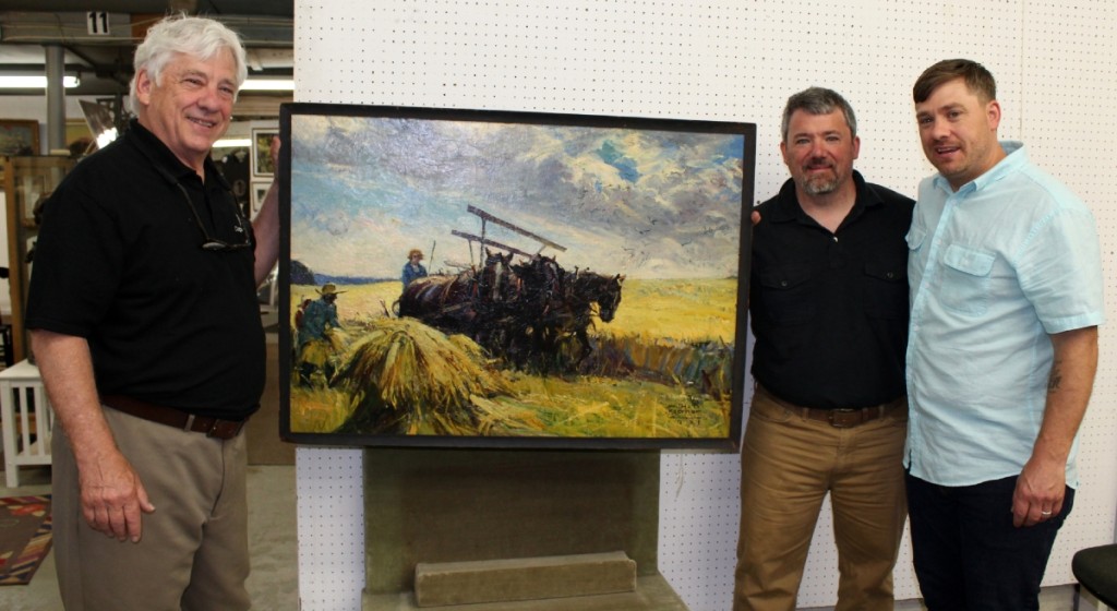 From left, Copake paterfamilias Mike Fallon and sons Seth and Evan stand with the sale’s top lot, a farming illustration by William Koerner (1878–1938) that left the gallery at $22,230.